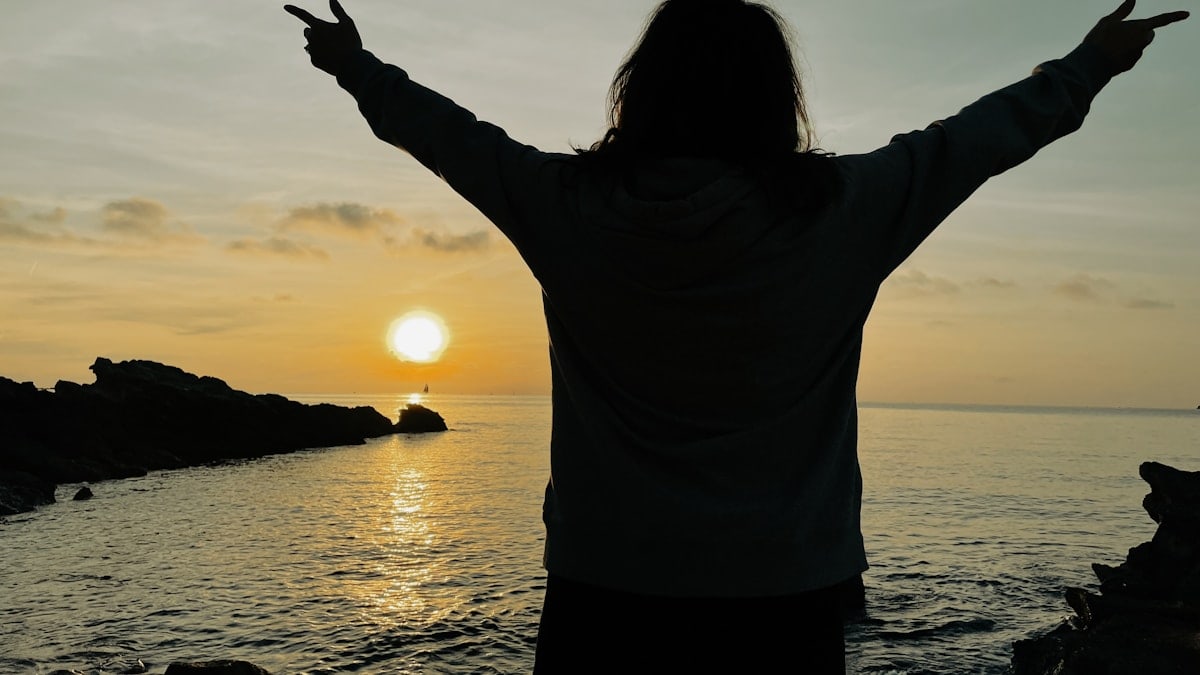 a person standing on a beach with their arms outstretched